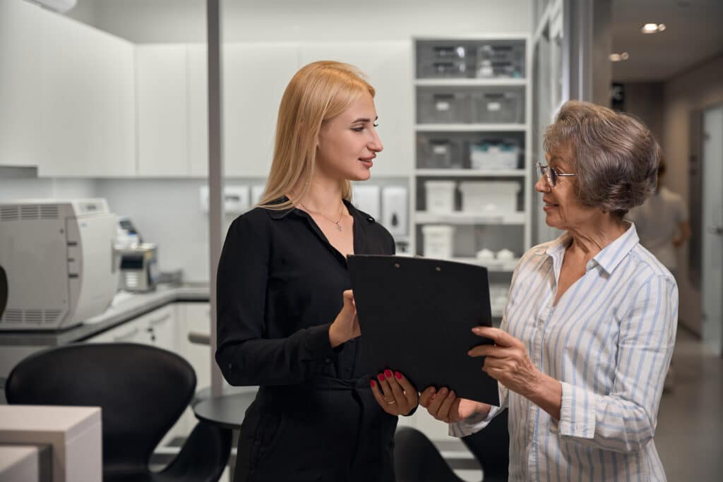 Clinic administrator consults elderly lady in dental clinic
