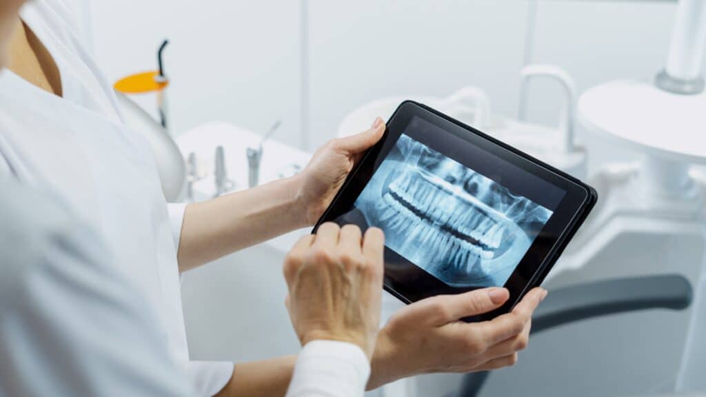 a dentist showing dental xray on tab device at Newport Beach Dental Solutions